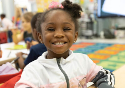 A young girl in a classroom smiling.