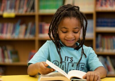 طفل يقرأ كتابًا على طاولة في المكتبة.