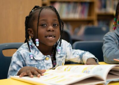 فتاة صغيرة تجلس على طاولة وتقرأ.