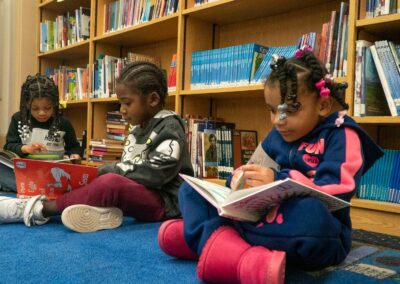 أطفال صغار يقرؤون على سجادة في مكتبة.