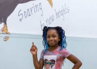 فتاة تقف أمام لوحة جدارية مكتوب عليها "الصعود إلى آفاق جديدة".