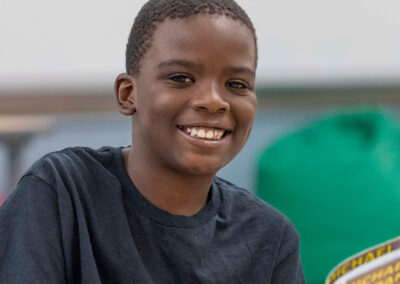 صبي يبتسم وهو يحمل كتاباً في يده.