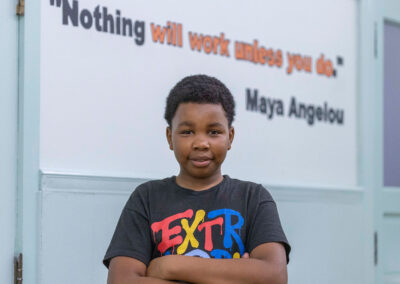 صبي يقف وذراعاه متقاطعتان أمام لوحة جدارية مكتوب عليها "لن ينجح شيء ما لم تفعله أنت. - مايا أنجيلو"