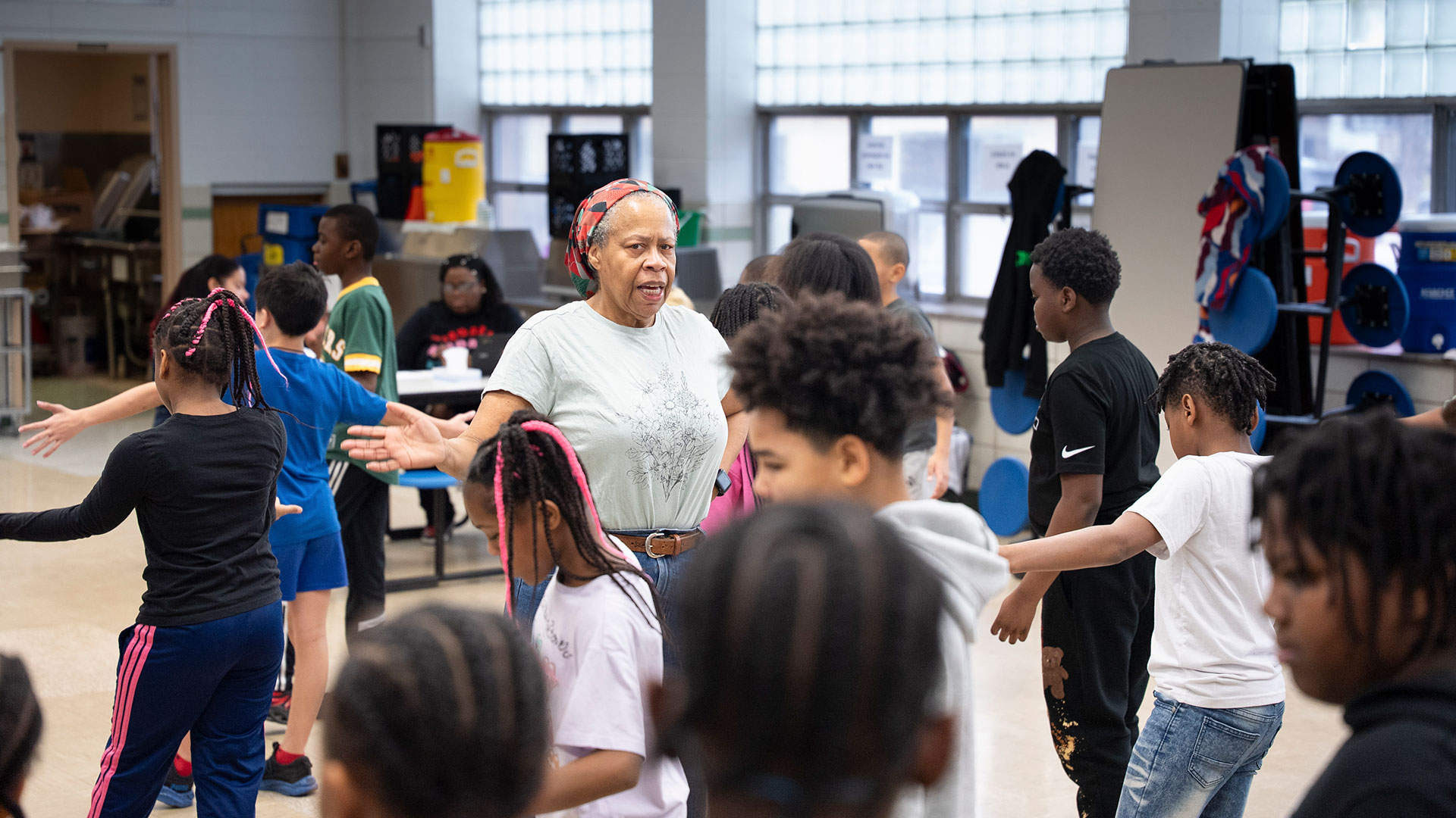 Children in a studio follow along with the movements of a teacher.