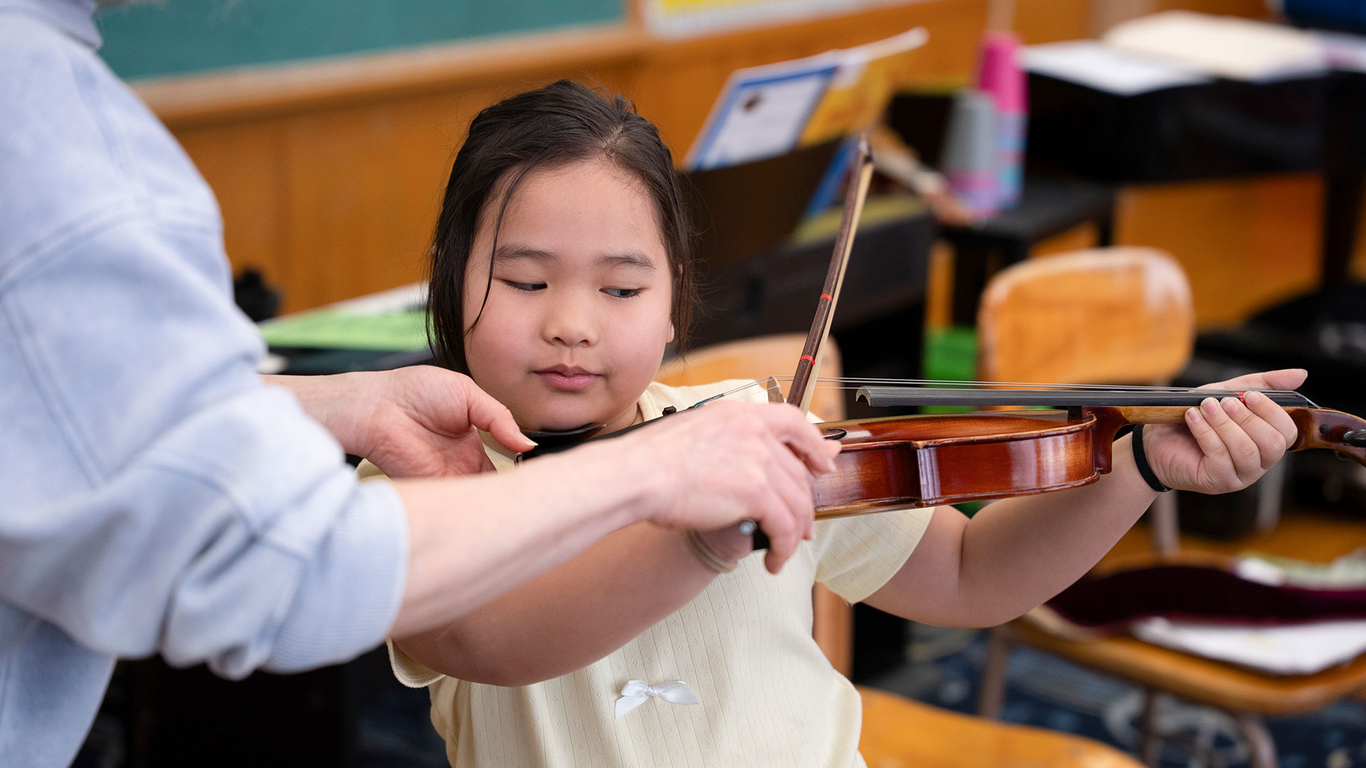 A young child being taught the violin.