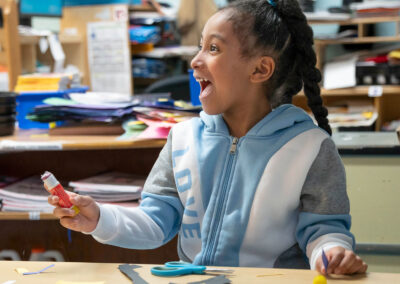 A girl in a classroom smiling.