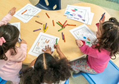 Overhead view of young children coloring at a table.