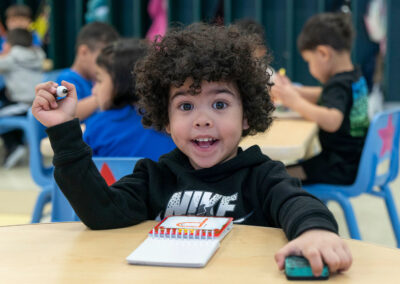 A young child at a table with a large smile.