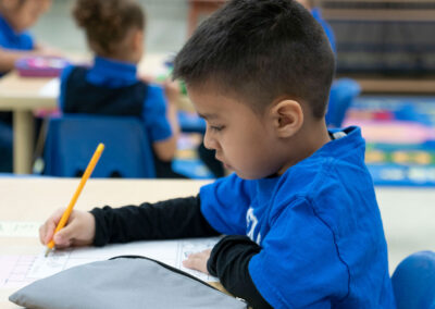 A young boy writing his name on a worksheet.