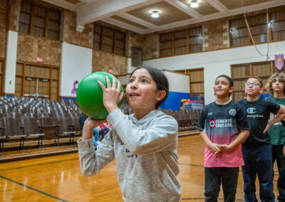 Children wait in line behind a child throwing a ball.