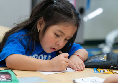 A young girl at a table coloring.