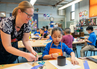 An art teacher helps her young student with her artwork.