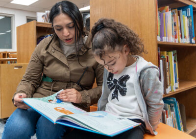 Una niña y su profesora leyendo un libro ilustrado.