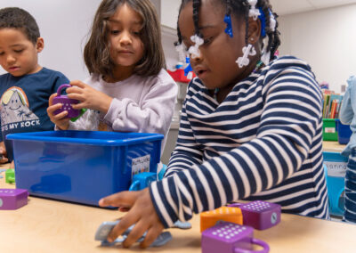 Niños pequeños jugando con candados matemáticos de colores.