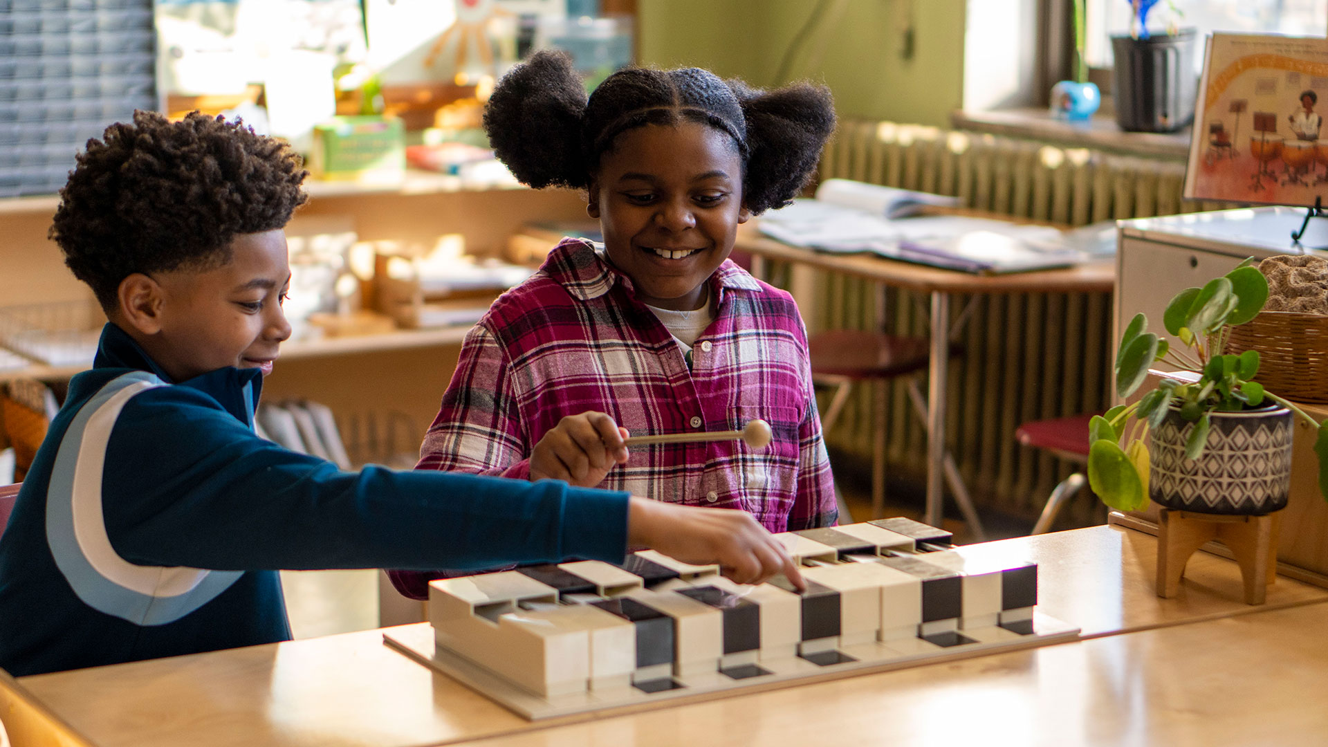 Two students smile as they play a xylophone.