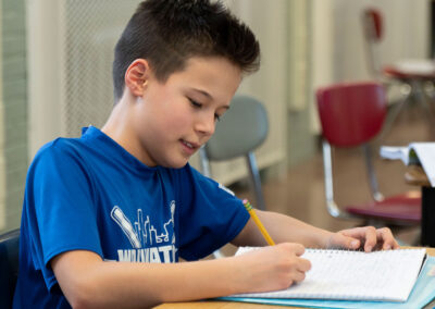 A child in a classroom writing in a notebook.