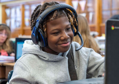 A student with headphones uses a computer.