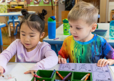 Two young children at a table coloring.