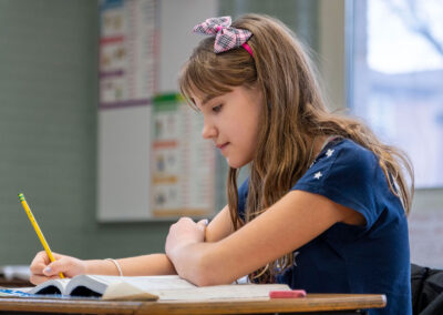 A child sitting at a desk writing in a workbook.