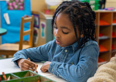 A young child at a table coloring.