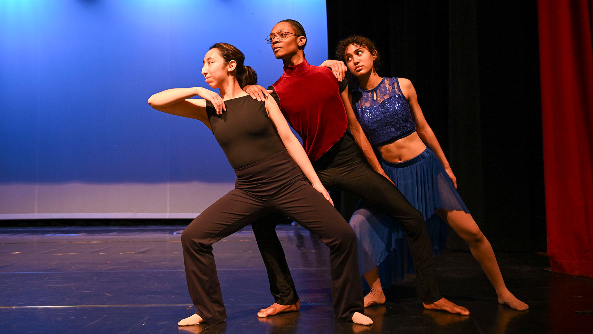 Three students dancing on a stage.