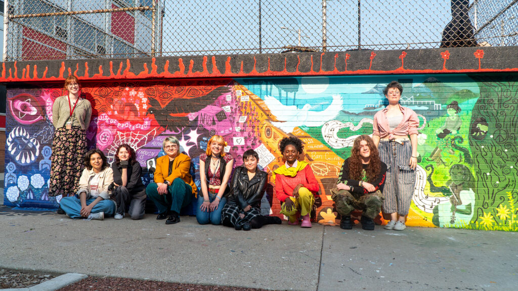 Students in front of a colorful mural.
