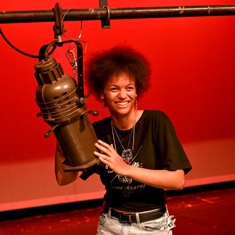 A person adjusting a stage light.