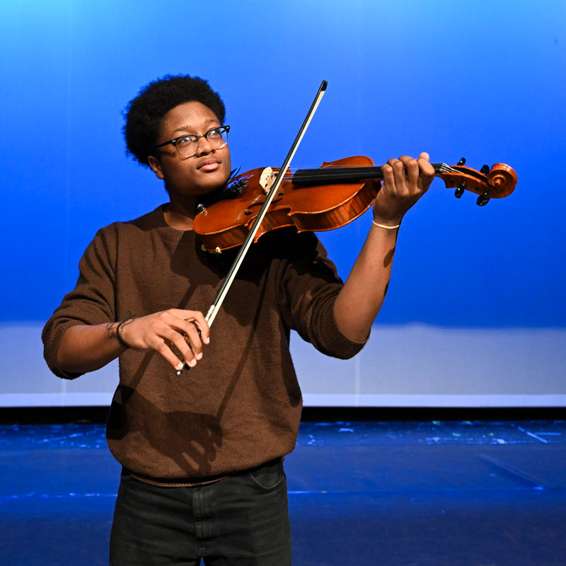 A boy playing violin on a stage.