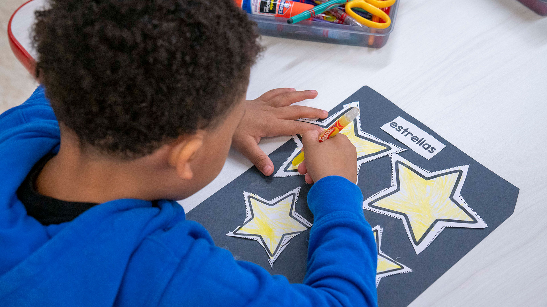 Overhead view of a young child coloring stars.