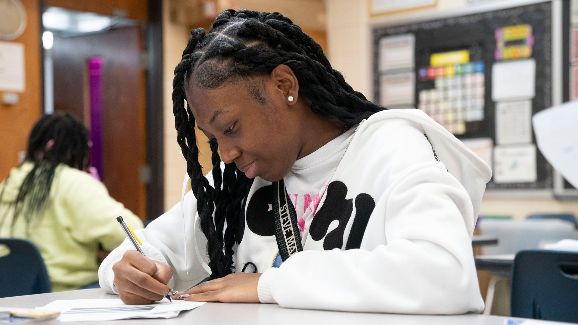 A student in a classroom writing.