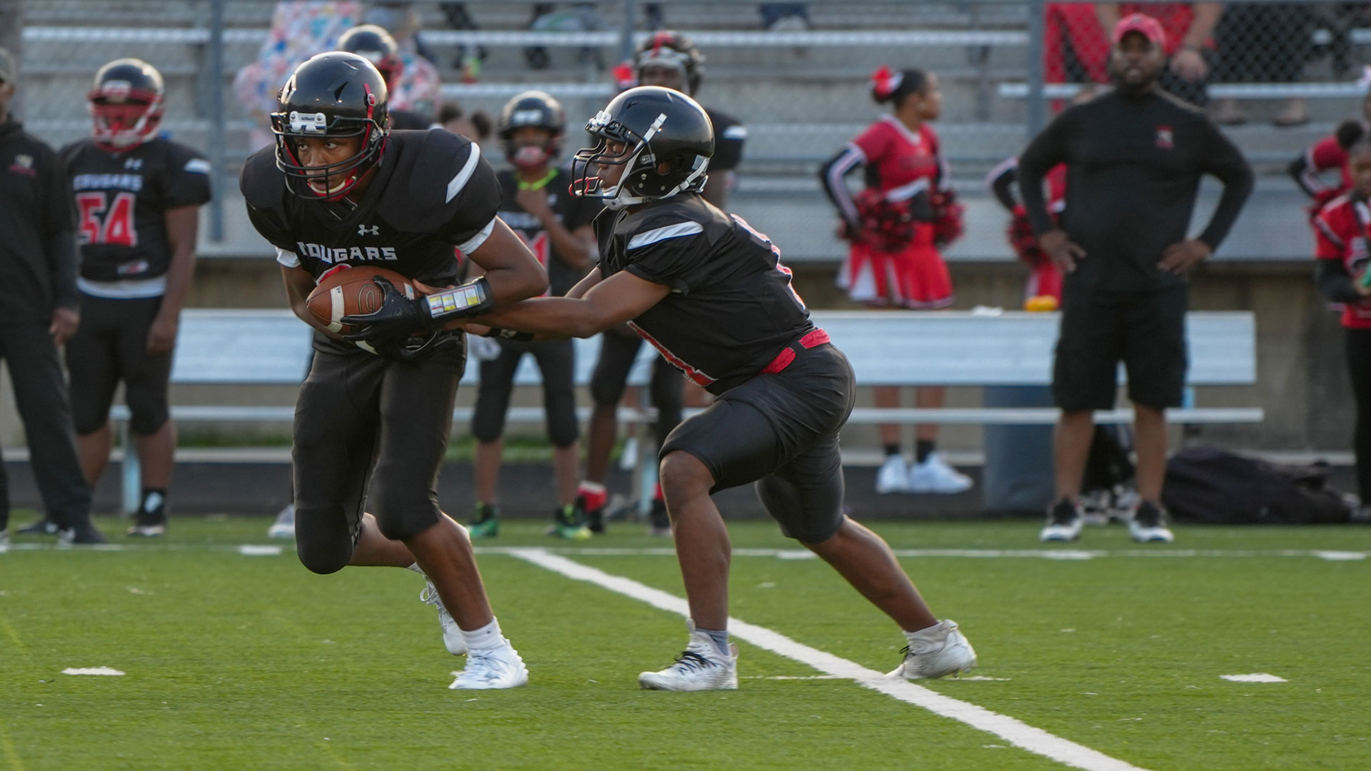 A quarterback handing off the football to a running back.