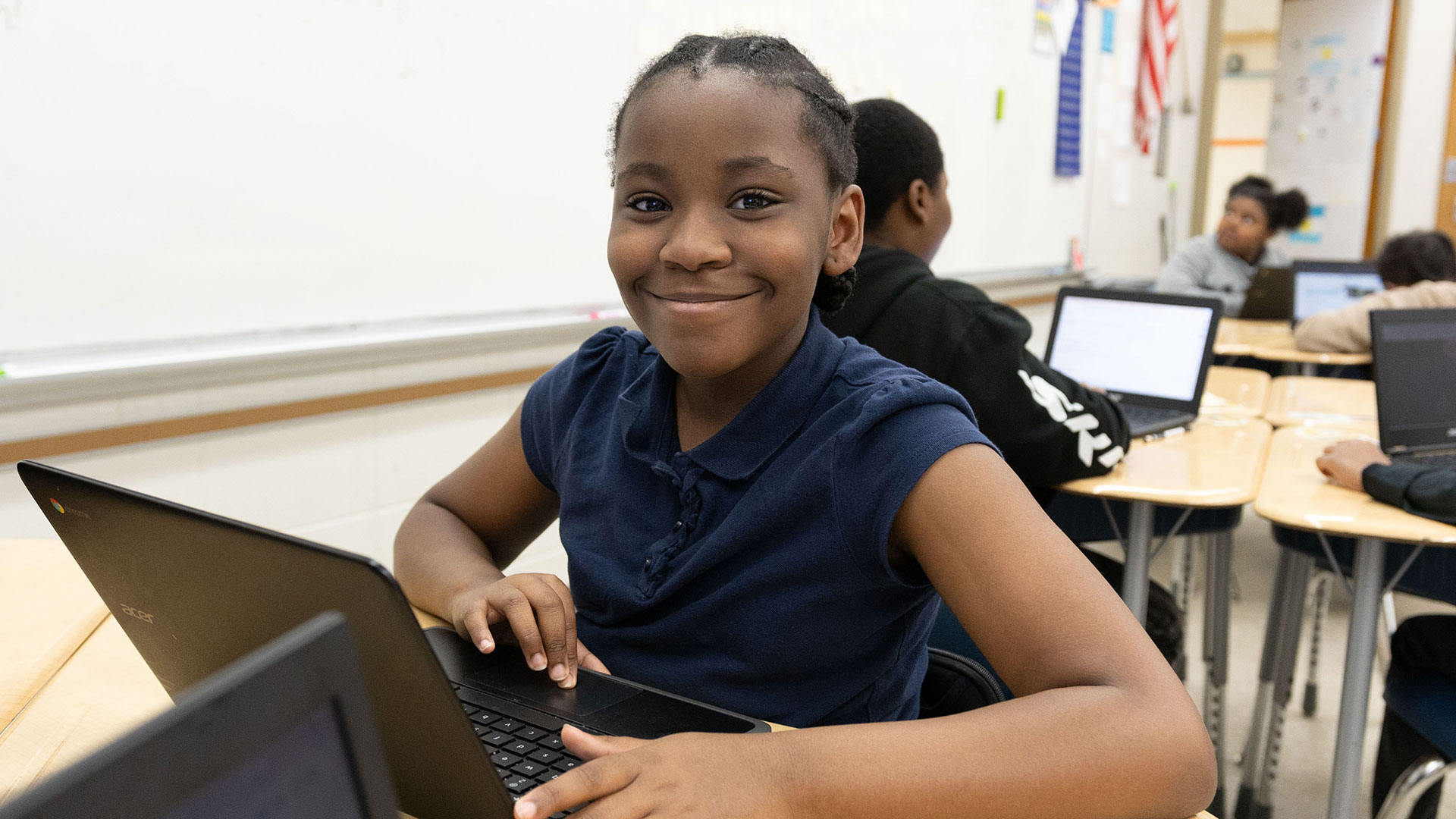 A student smiles as they uses a computer.