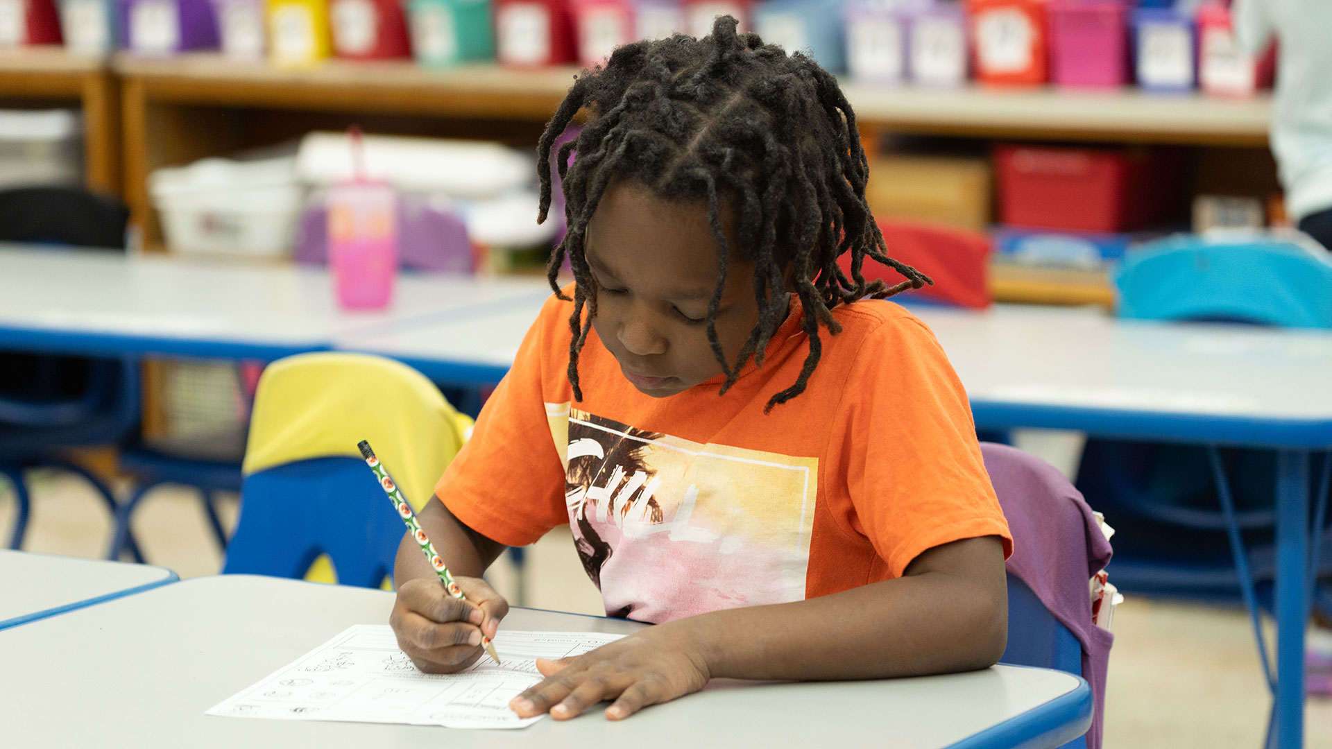A young boy writing on a worksheet.