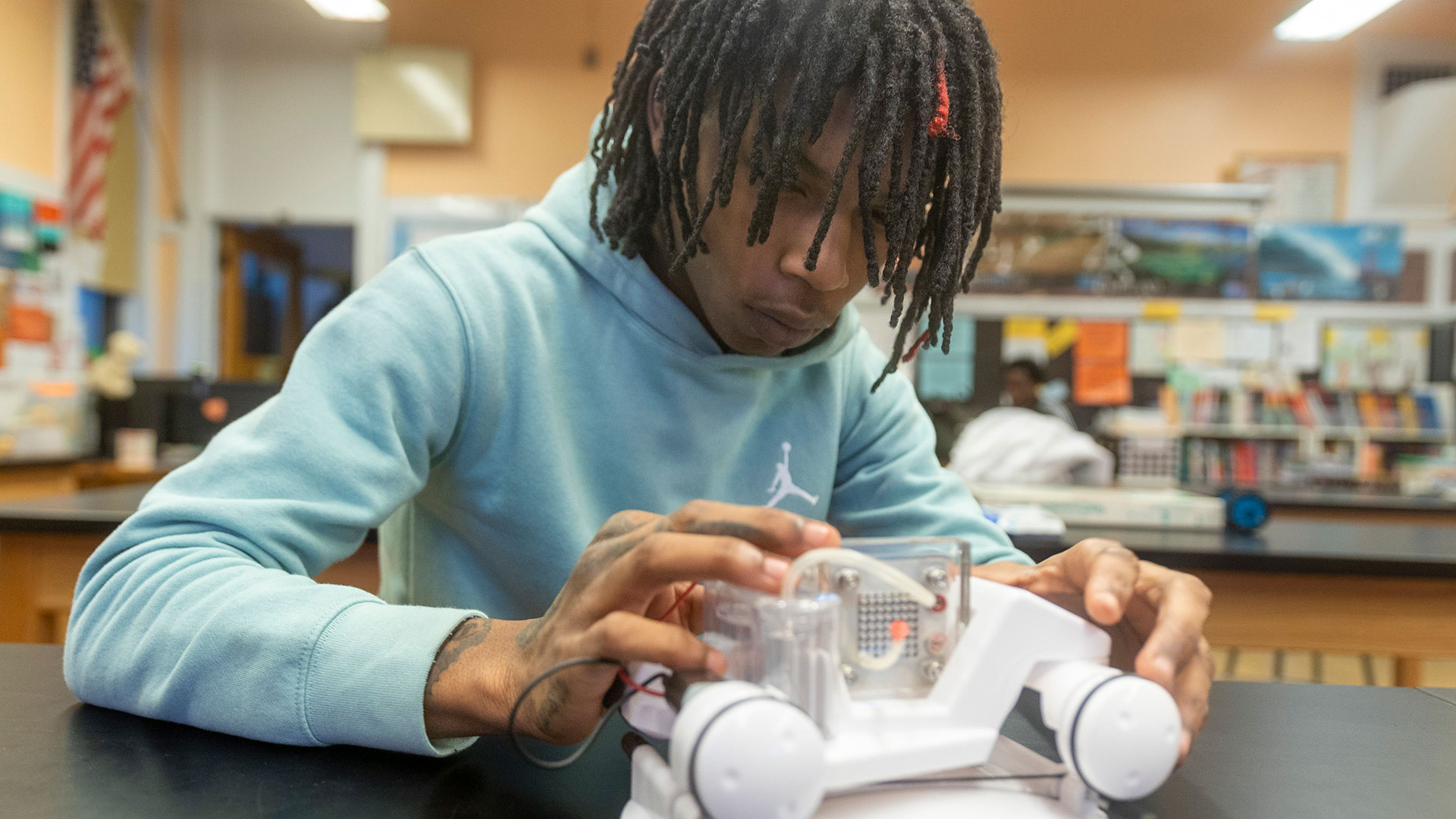 A student looking at a small robotic machine.