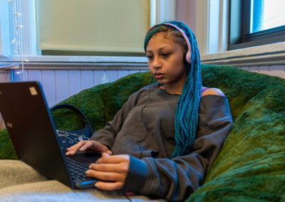 A girl in a large beanbag chair using a computer.