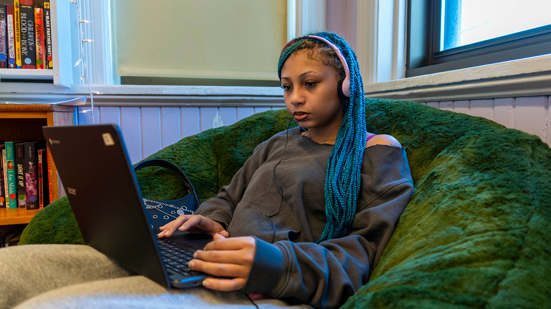 A girl in a large beanbag chair using a computer.