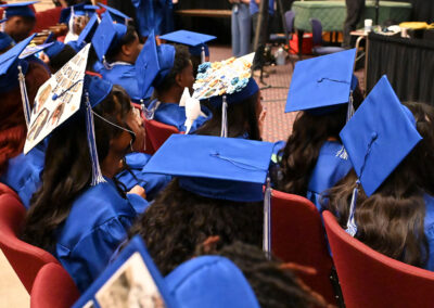 Graduates in caps and gowns sit in an auditorium.