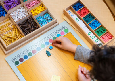 Overhead view of a young child placing small blocks on a number line.