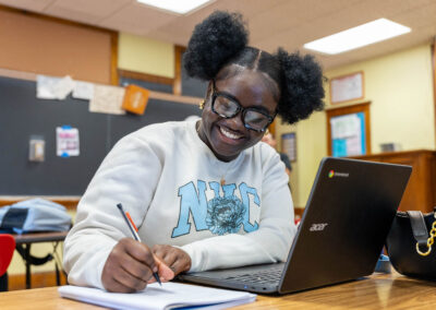 A girl smiles as she writes.