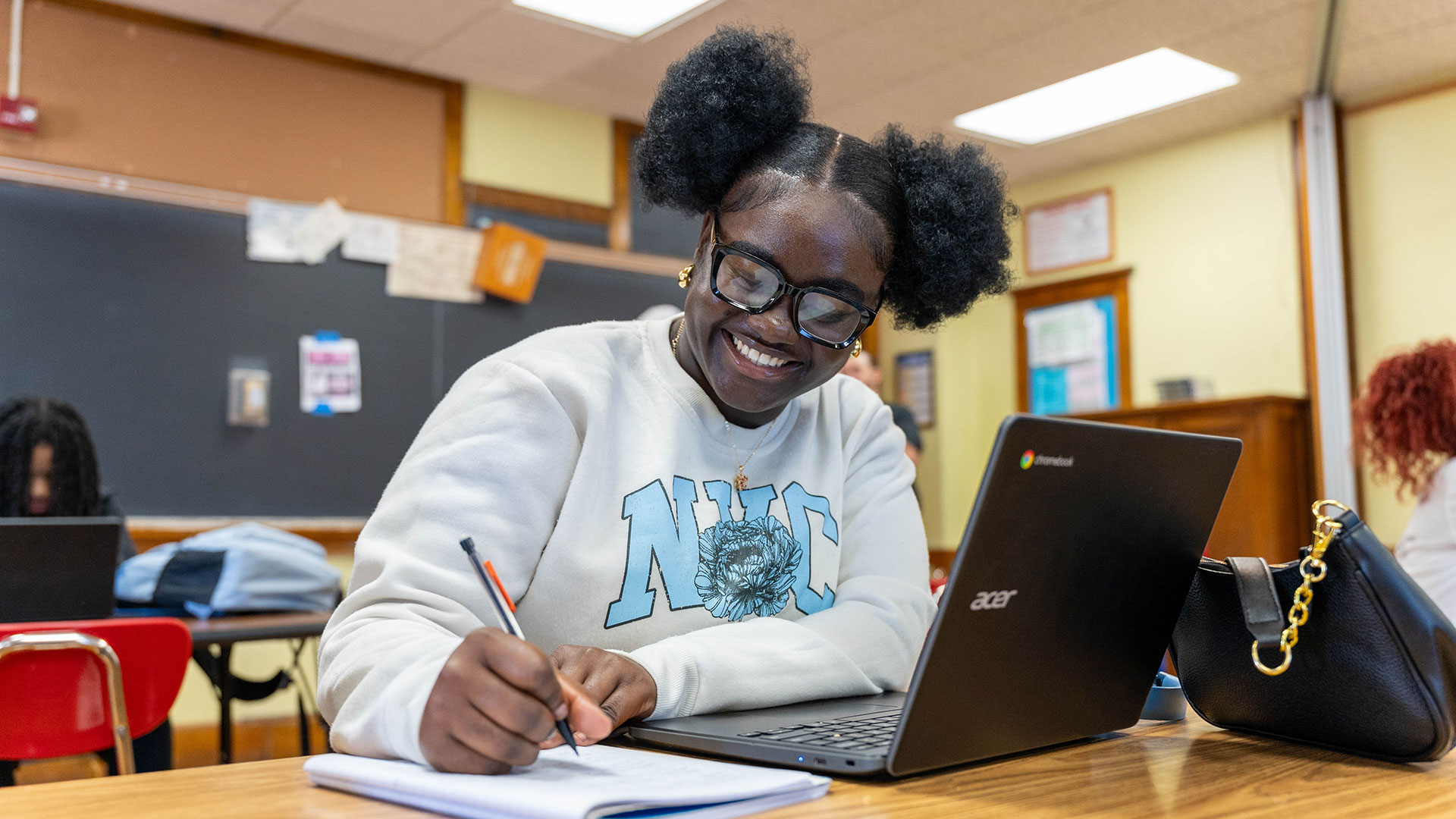 A girl smiles as she writes.