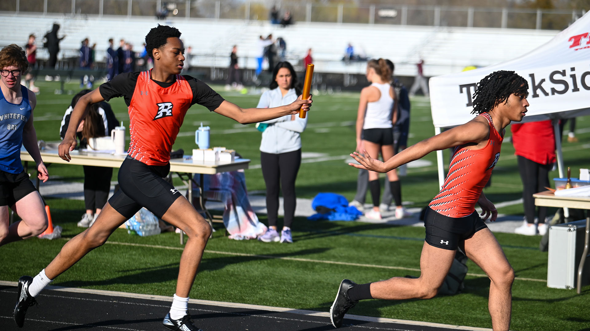 Track and field athletes passing a baton.