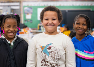 Three children standing next to one another smiling.