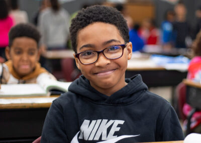 A boy in a classroom smiling.