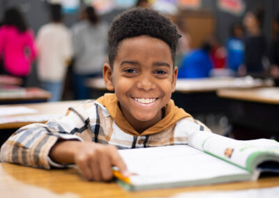 A boy at a desk smiling.