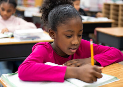 A girl at a desk writing in a workbook.