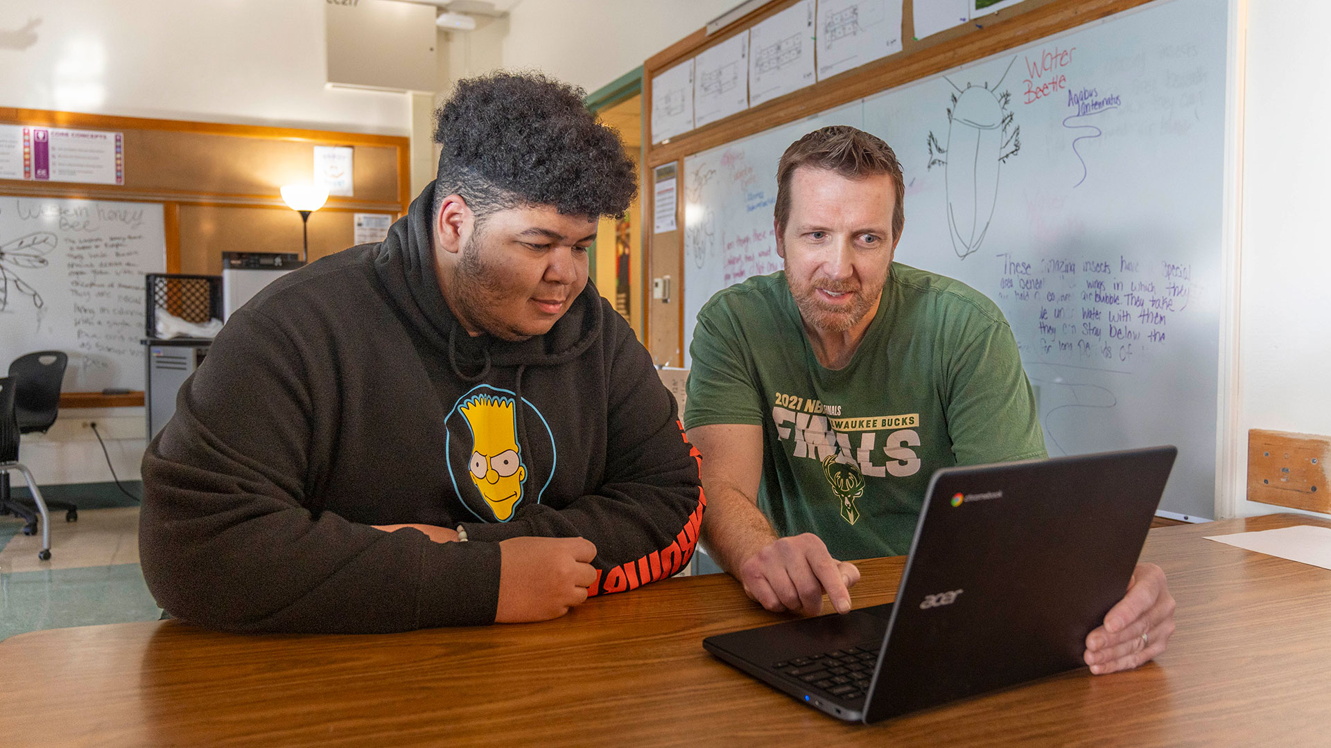 A teacher and student looking at a computer screen.