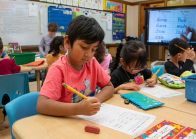 A classroom of young students practice writing.