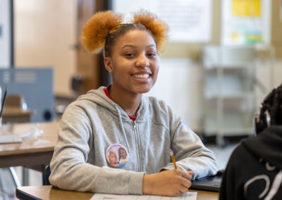 A girl smiles while writing.