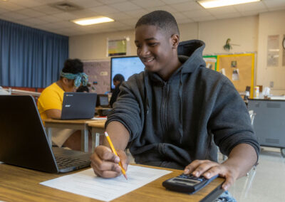 A student looks at a computer as they write on a piece of paper.