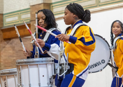 Young women in colorful uniforms drumming.